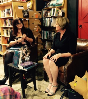 Two women sitting in front of a wall of bookshelves. They are immersed in conversation.